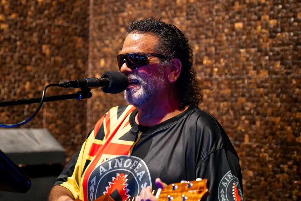 Musician performs outdoors in a tropical travel setting.