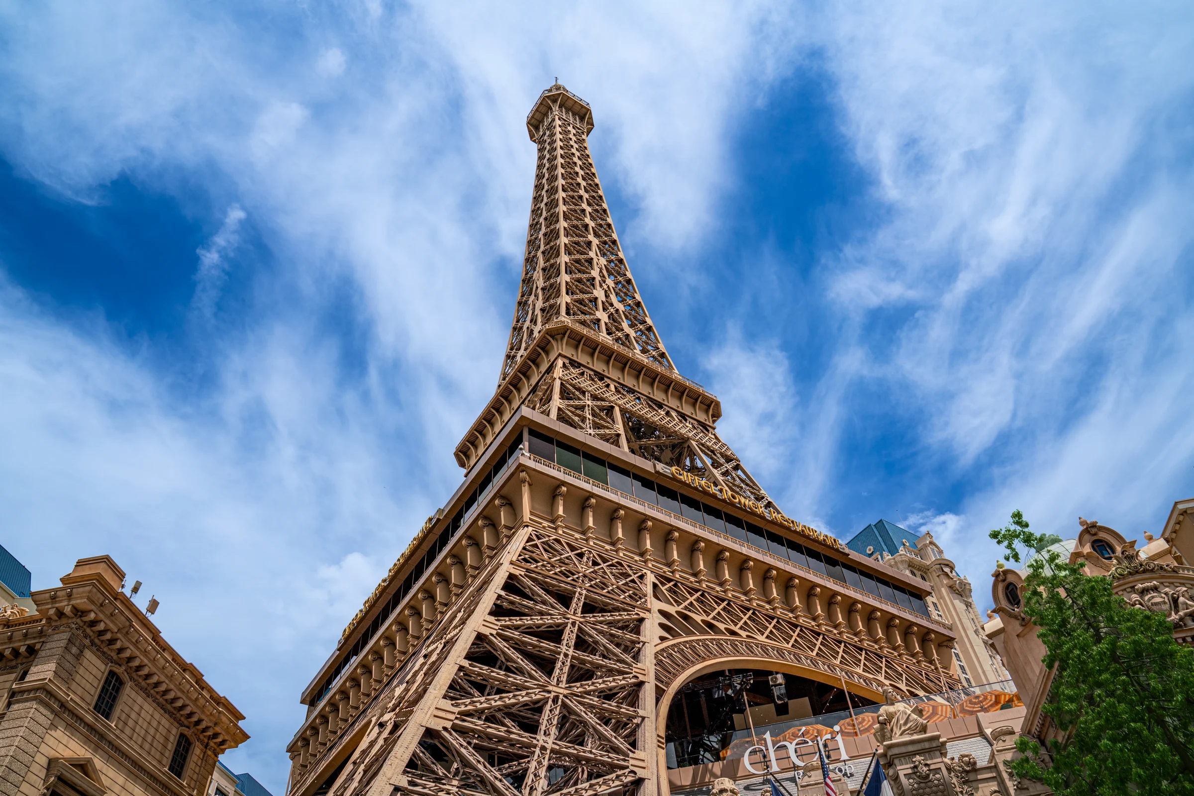 The Paris Las Vegas Eiffel Tower replica rises beneath streaked clouds in daylight.
