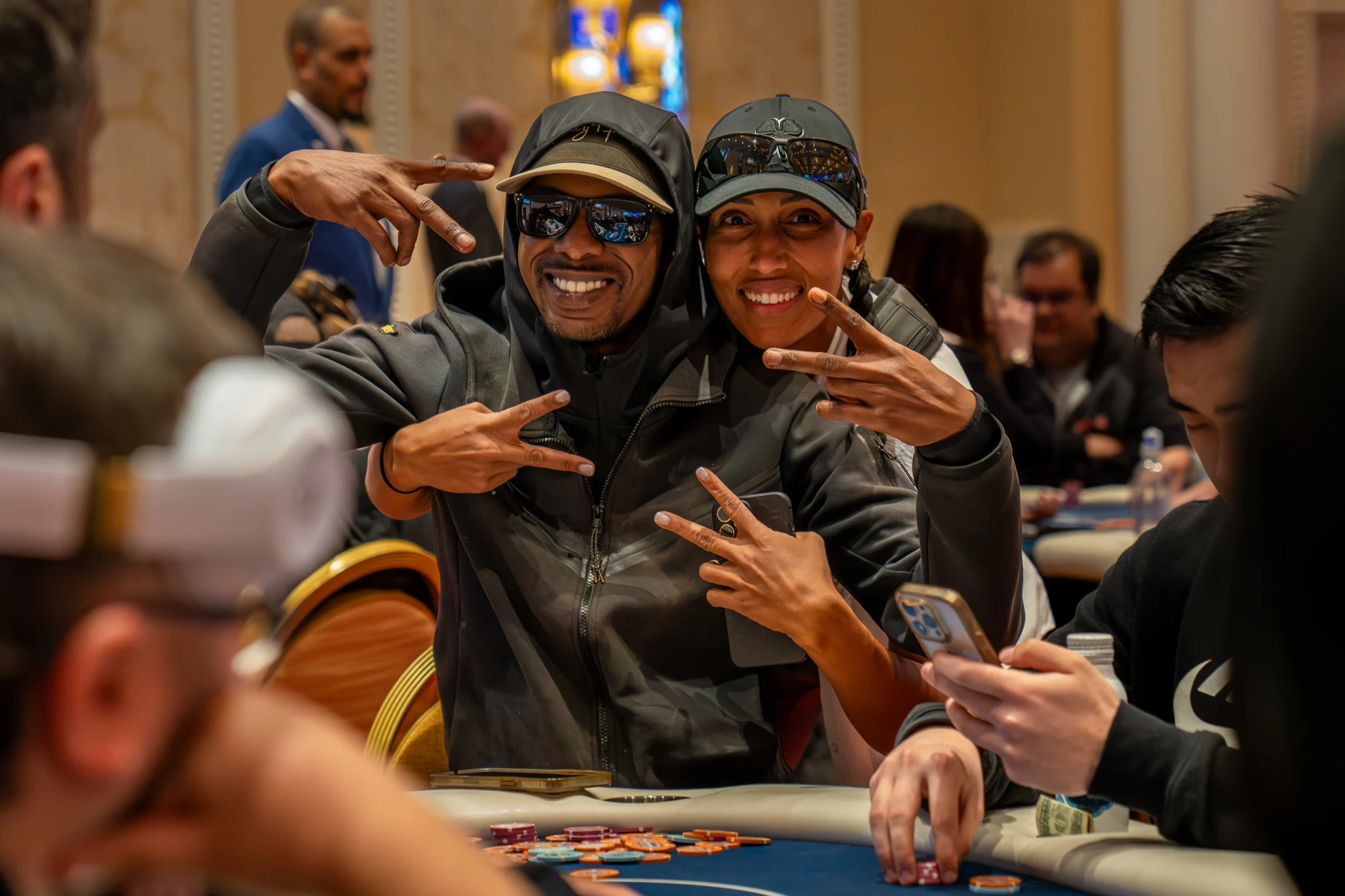 Two smiling people pose together beside poker chips during a lively tournament.