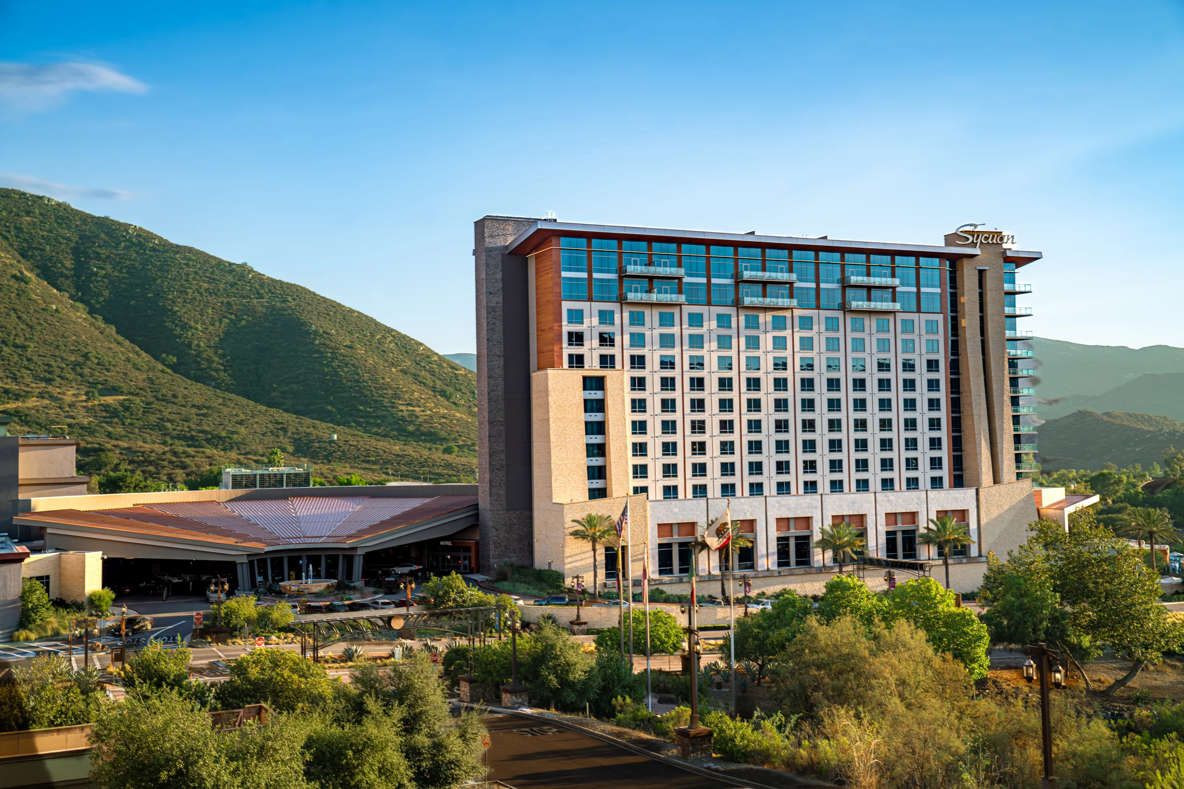 Sycuan Casino Resort rises against green hills beneath a clear blue sky.