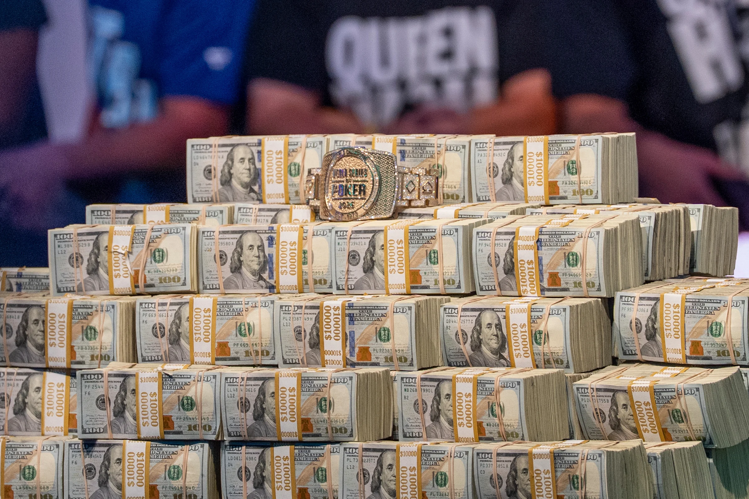 Stacks of cash form a display topped by a World Series of Poker bracelet.