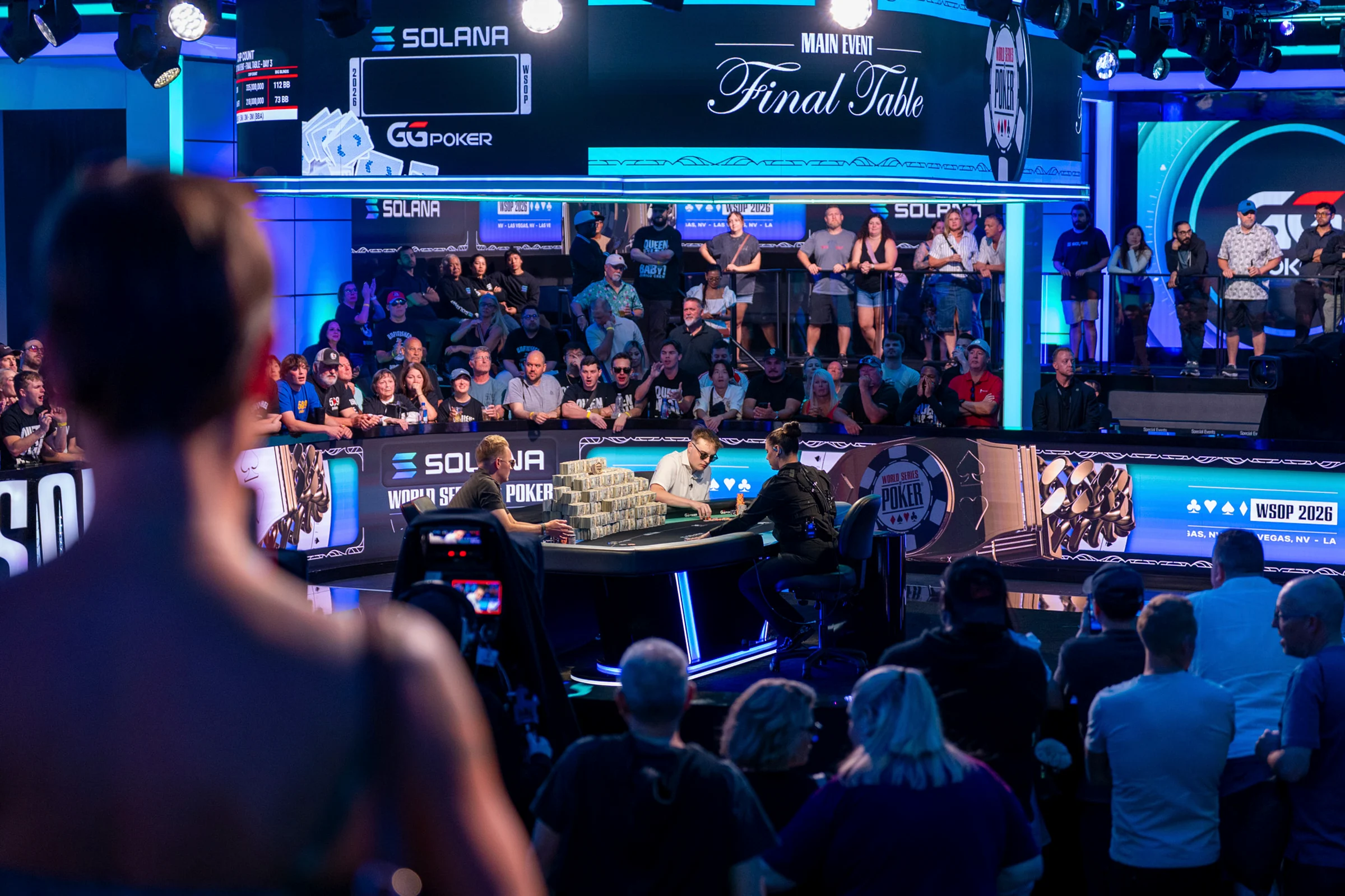 A packed arena surrounds the illuminated 2026 WSOP Main Event final table.